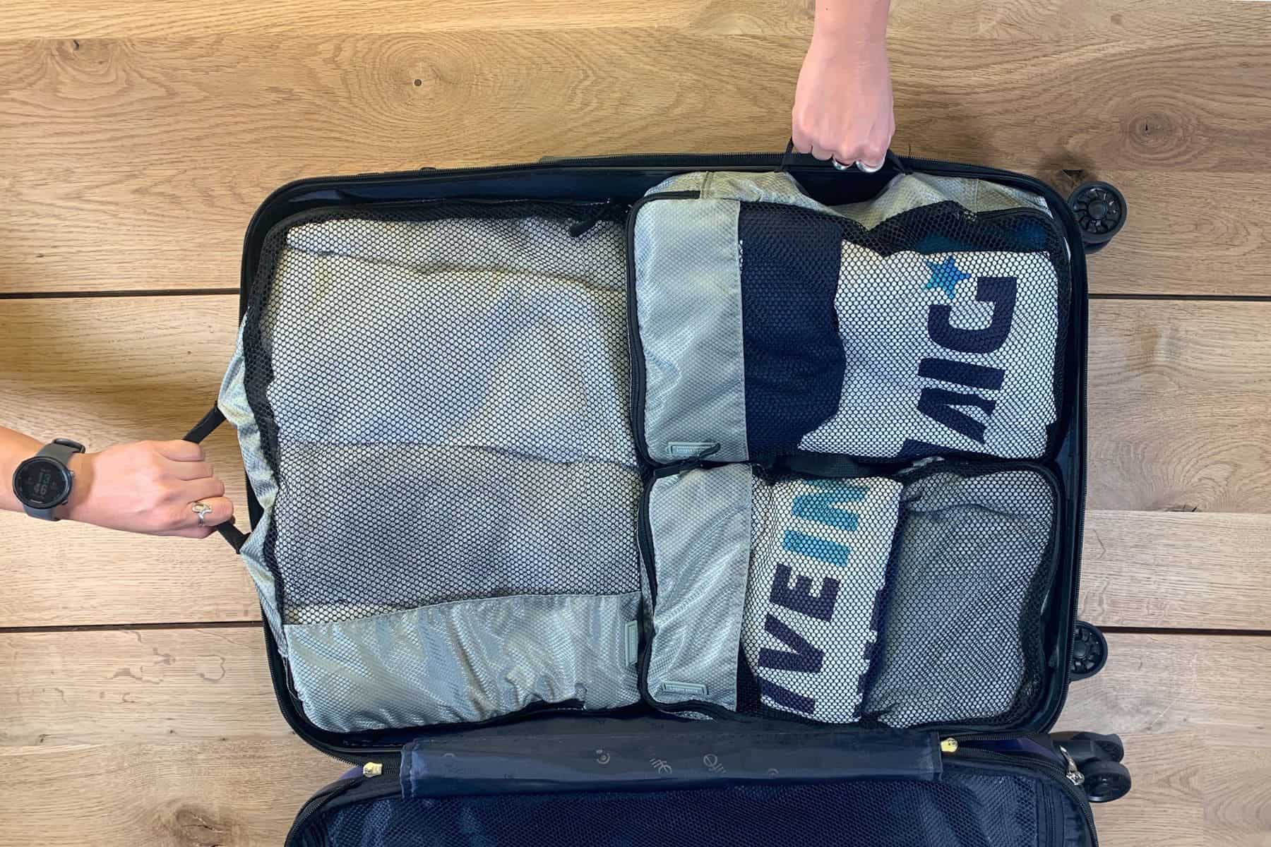Amazon Basics Packing Cubes inside a suitcase. One large and two medium packing cubes in gray.
